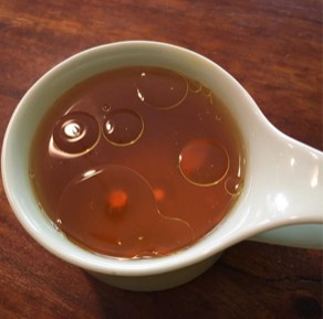 Dark gold liquid in a white ceramic ladle