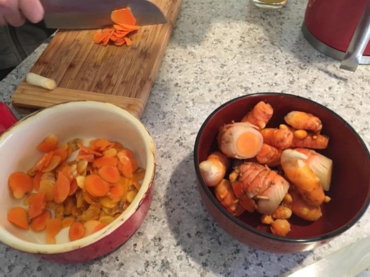 two bowls sitting on a marble counter with whole and sliced raw turmeric