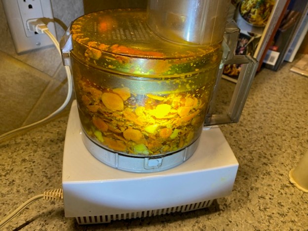 Fresh turmeric slices being chopped in a food processor
