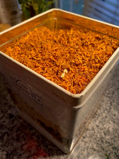 Dried golden turmeric stored in a square metal tin