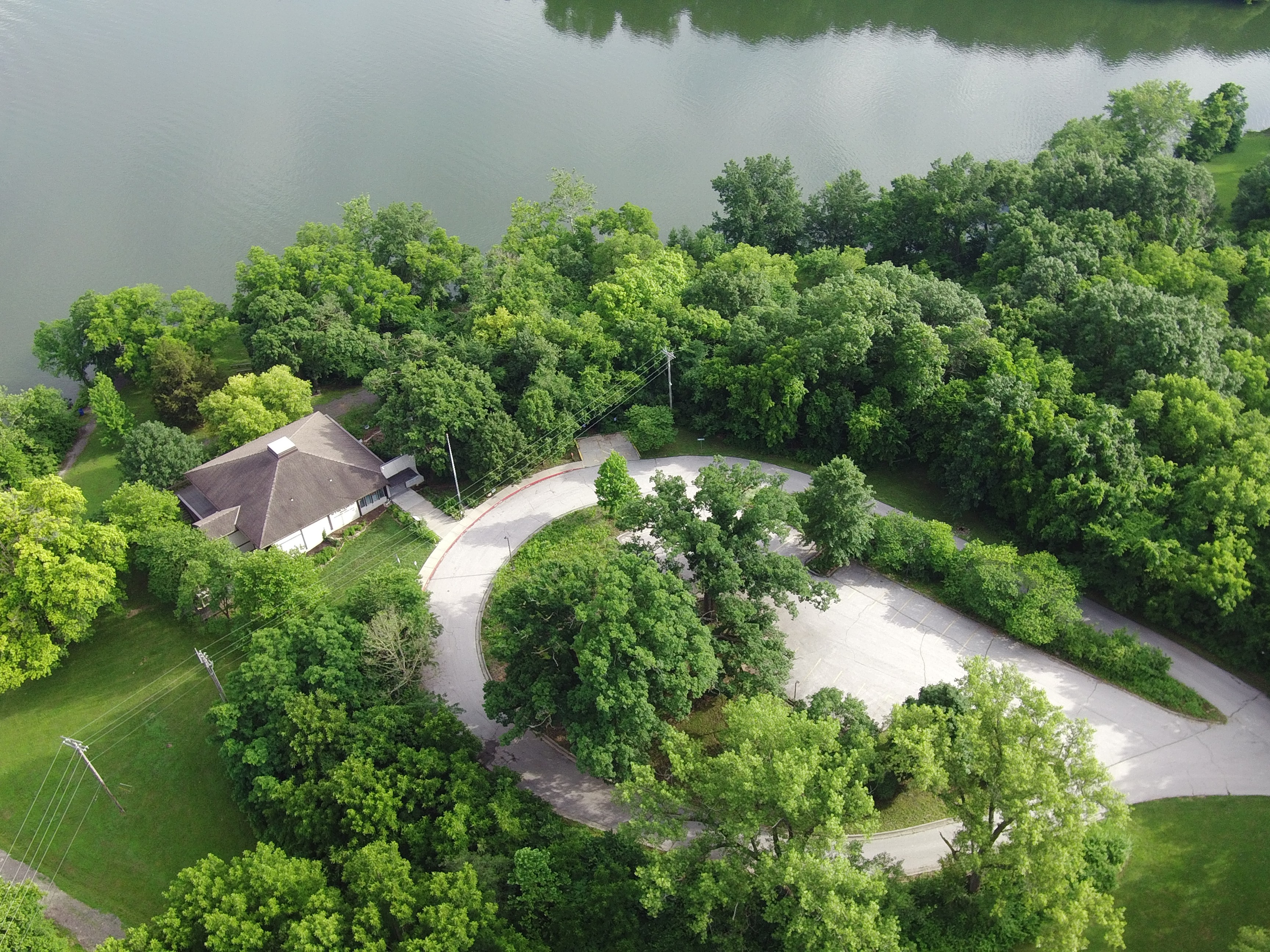 aerial view of building next to lake surrounded by trees