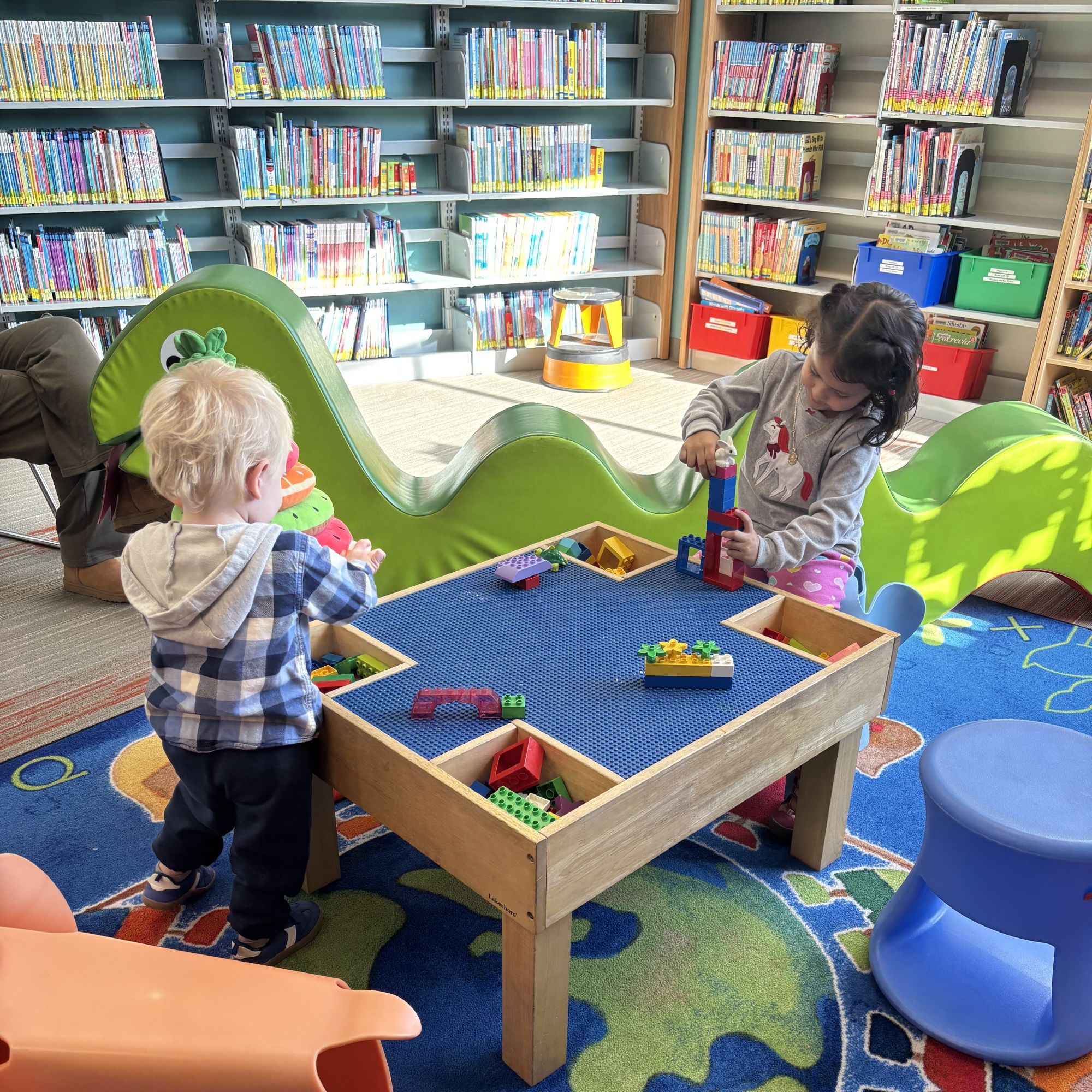 2 toddlers playing at a lego table inside the kids area of South Branch Library