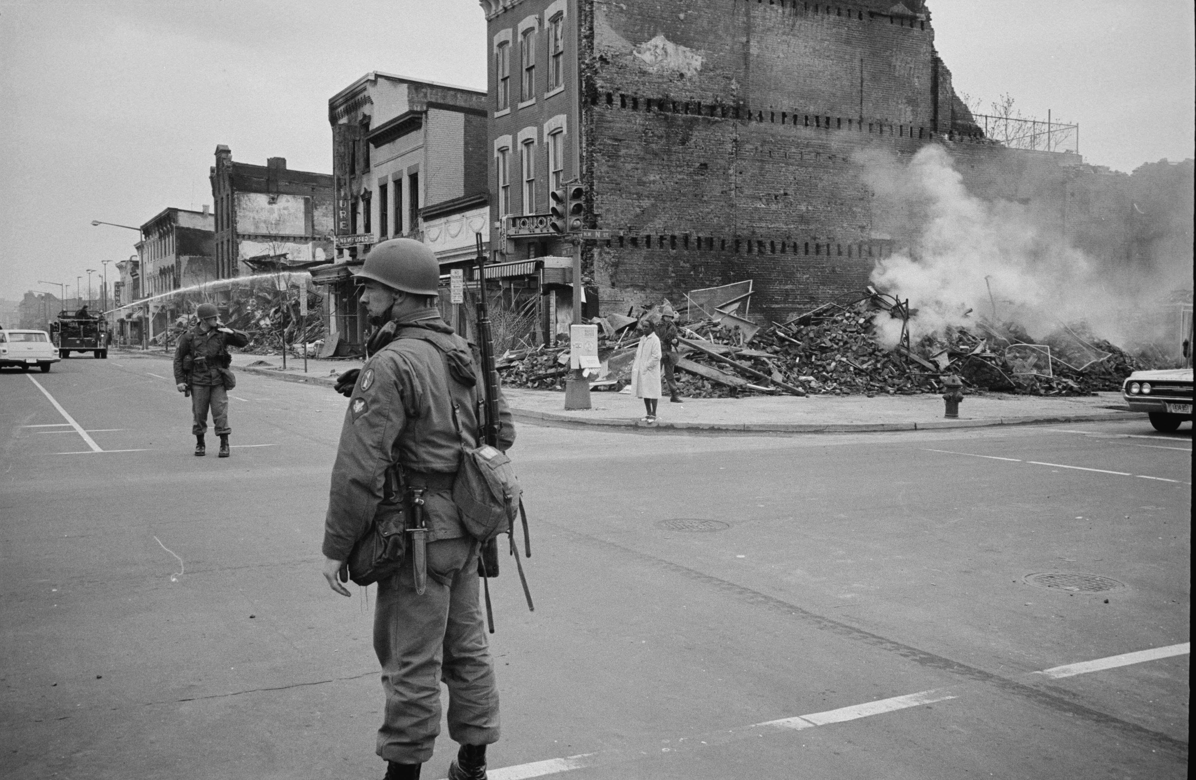 Photograph from the 1968 riot in Washington, D.C. following the assassination of Martin Luther King, Jr. It shows a soldier standing on the street near a ruined building.