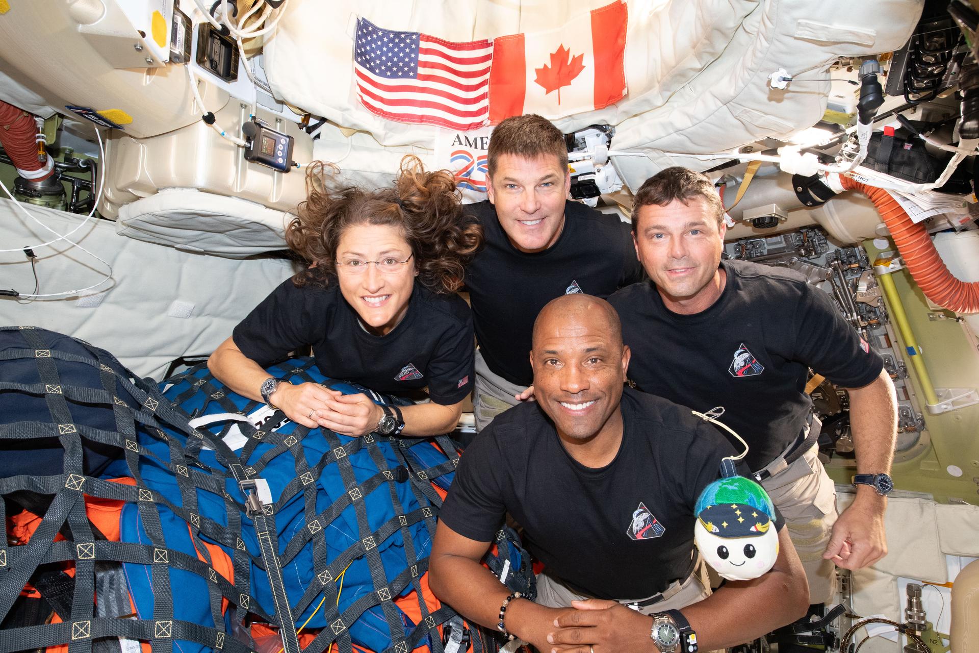 Artemis 2 crew, Reid Wiseman, Victor Glover, and Christina Koch NASA, and Canadian Space Agency astronaut Jeremy Hansen on the Orion space capsule in microgravity with moon mascot plush Rise.
