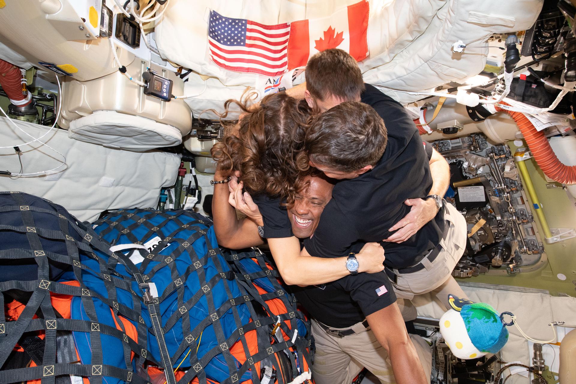 astronauts on the Artemis II mission hugging while in space