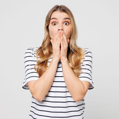shocked woman in striped shirt with hands covering mouth