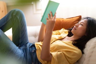 Young asian woman reading book relaxing on sofa