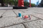 miniature people figurines on a brick sidewalk using construction equipment to remove a piece of bubble gum, image by Luke Pech
