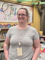 portrait of Maggi in the youth services department at Main Library wearing a grey t-shirt with her hair pulled back