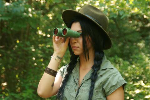 A person in the forest using binoculars 