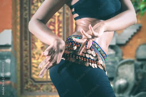 A person wearing belly dancing regalia and moving their hips.