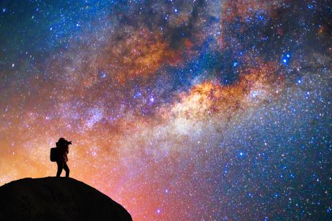 A person in the background taking pictures of the starry sky