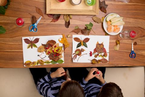 Two children using leaves and twigs to make a craft
