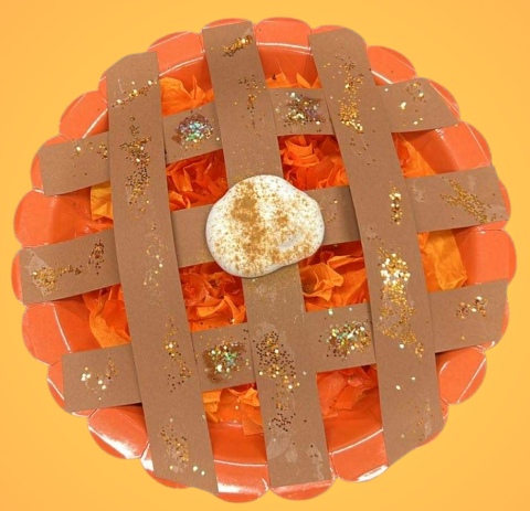 paper plate with tissue paper, brown paper strips and glitter made to resemble a pumpkin pie.