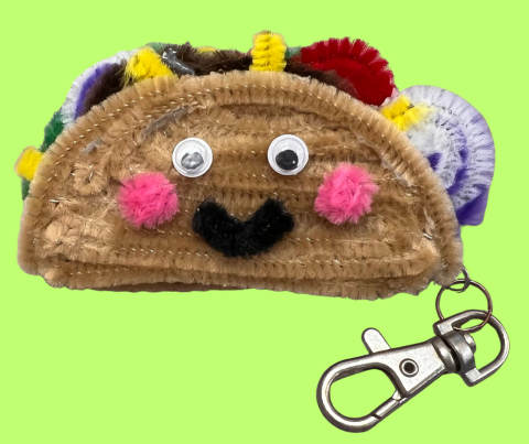 charm to attach to a bag or purse that looks like a taco with a smiling face made from pipe clearners