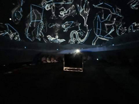 A dark background with stars and children looking up at thme