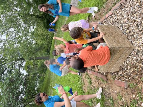 Children playing in a boat with adults spraying them outside of the boat