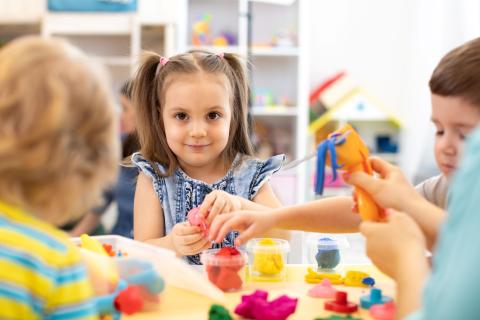 children sitting at a table playing with playdough