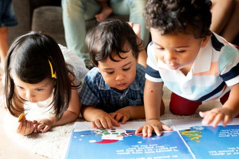 3 babies looking at a book on the floor