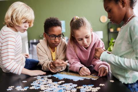 four children playing with puzzle pieces on a table