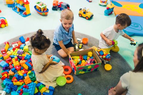 toddlers enjoying building blocks, cars, ships and other plastic toys in classroom