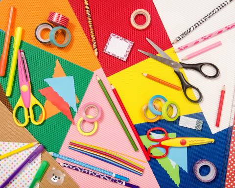A graphic showing a craft table with scissors, gel pens, color paper, pencils, highlighters, washi tape, and post-it notes. 