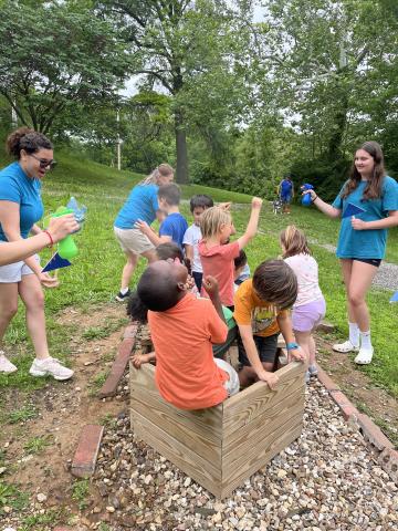 Children playing in a boat with adults spraying them outside of the boat