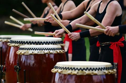 Close up of three men playing Japanese Taiko drums. 
