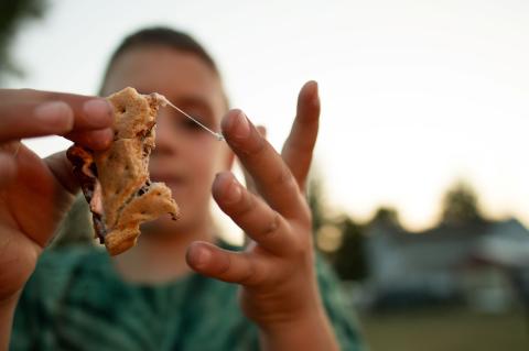 boy eating smore with marshmallow sticking to his fingers 