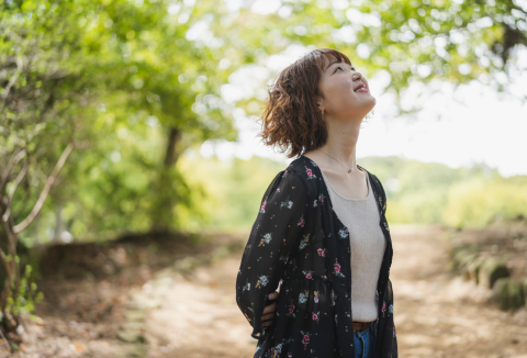 a person in the forest looking up at the trees smiling 