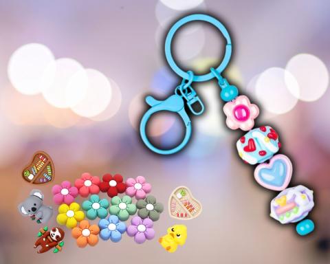 A picture of a clip that has charms attached to it. Some of the charms are library heart book shelves, different colored flowers, and animals.