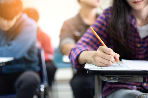 teenagers sitting at desks taking a test with pencils
