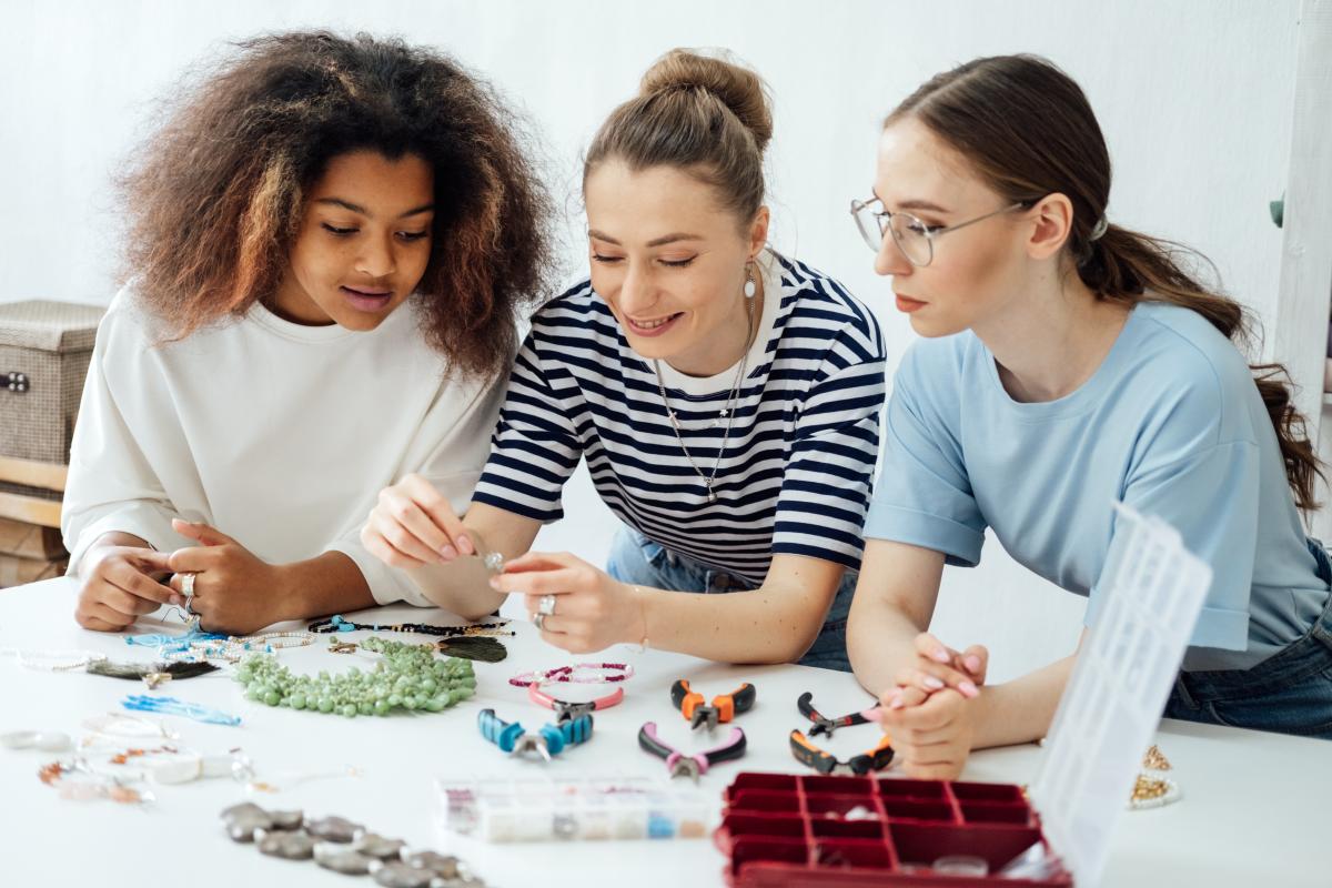 three women making jewelry together