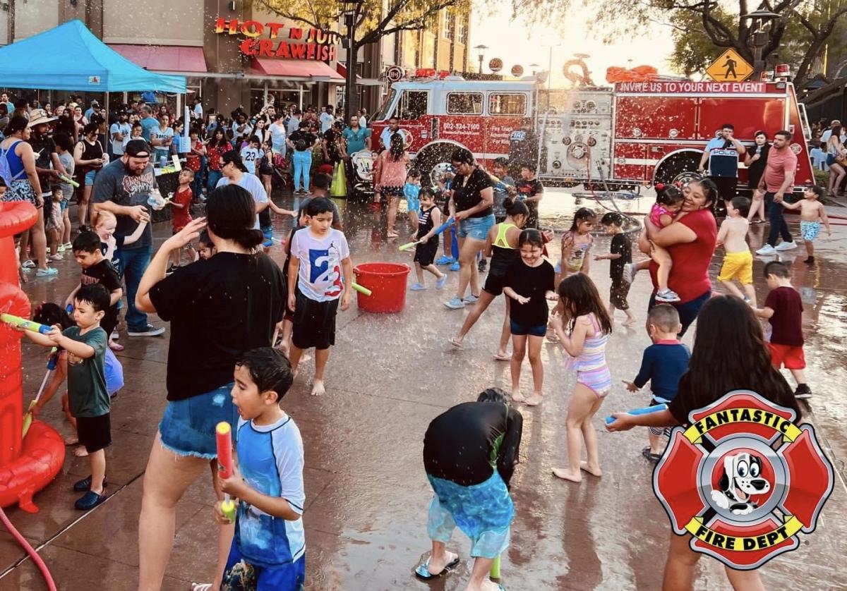 Children playing in spraying water with fire truck in background