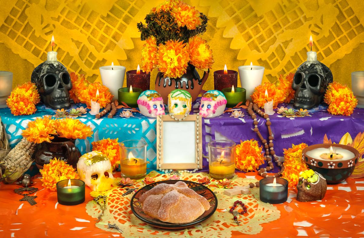 Day of the Dead altar featuring food, flowers, candles and skull decorations.