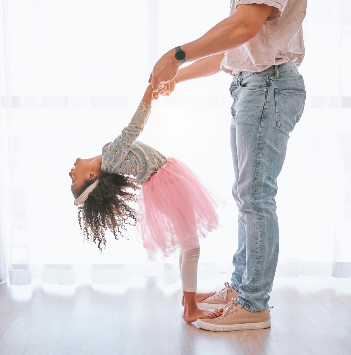 young girl in tutu dancing with her father