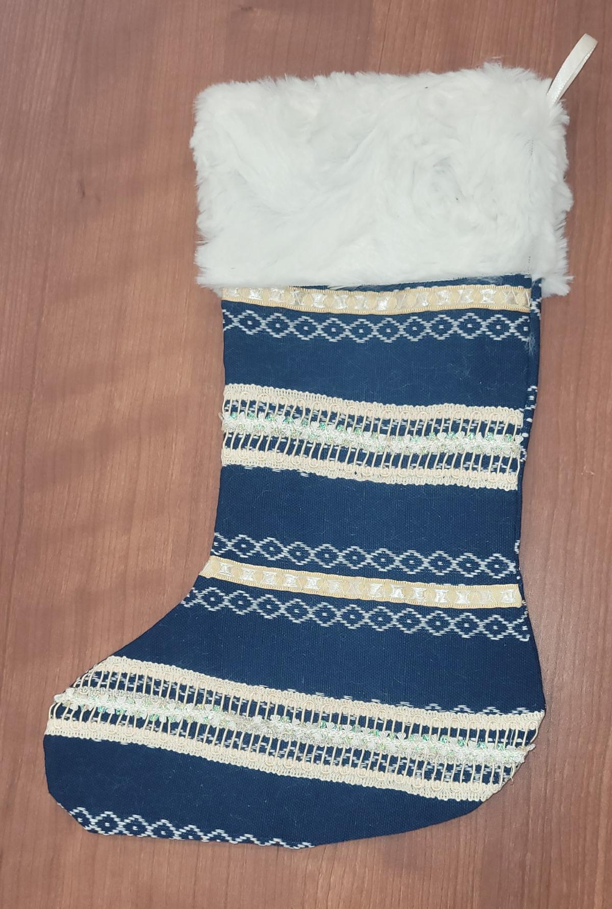 Blue Christmas stocking with ivory trim and a white fur cuff on a wooden background