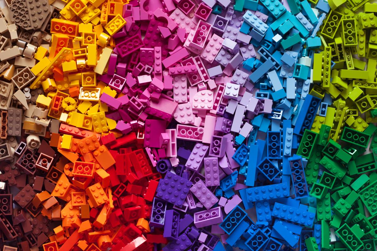 piles of legos spread on a flat surface in a rainbow color pattern