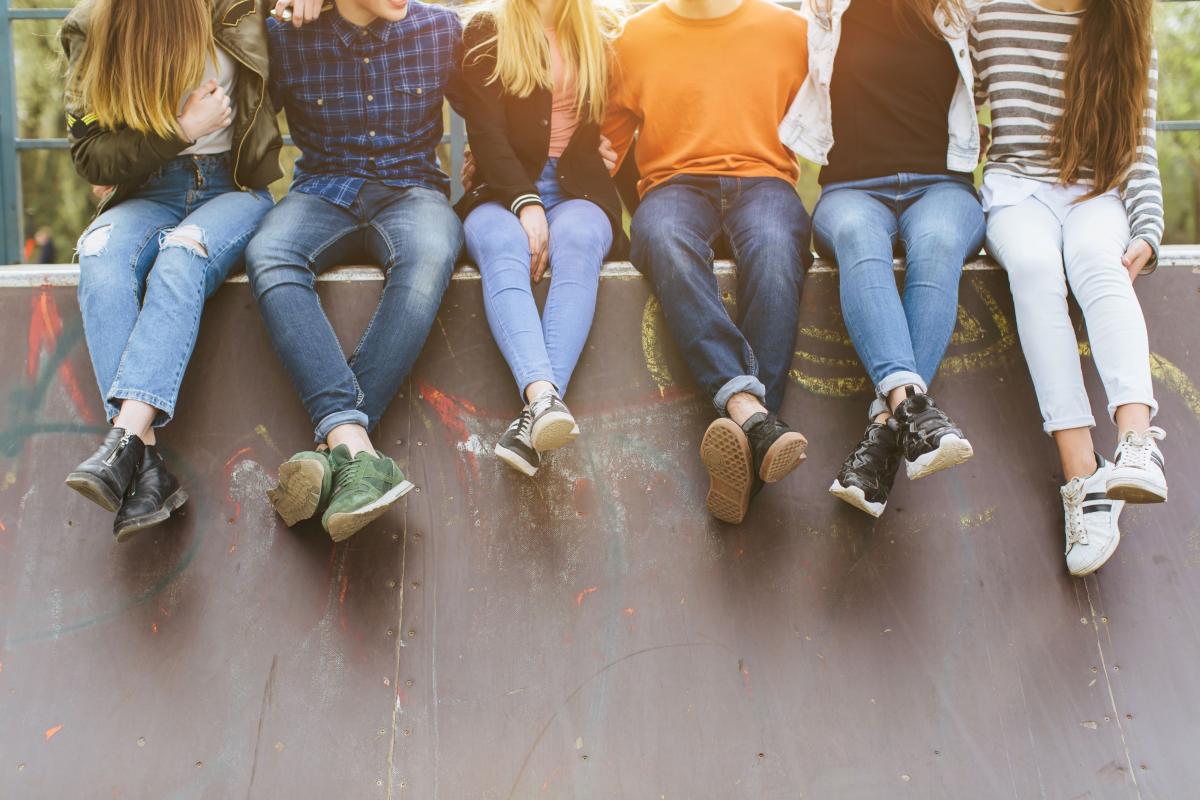 teenagers sitting on a wall with feet hanging down