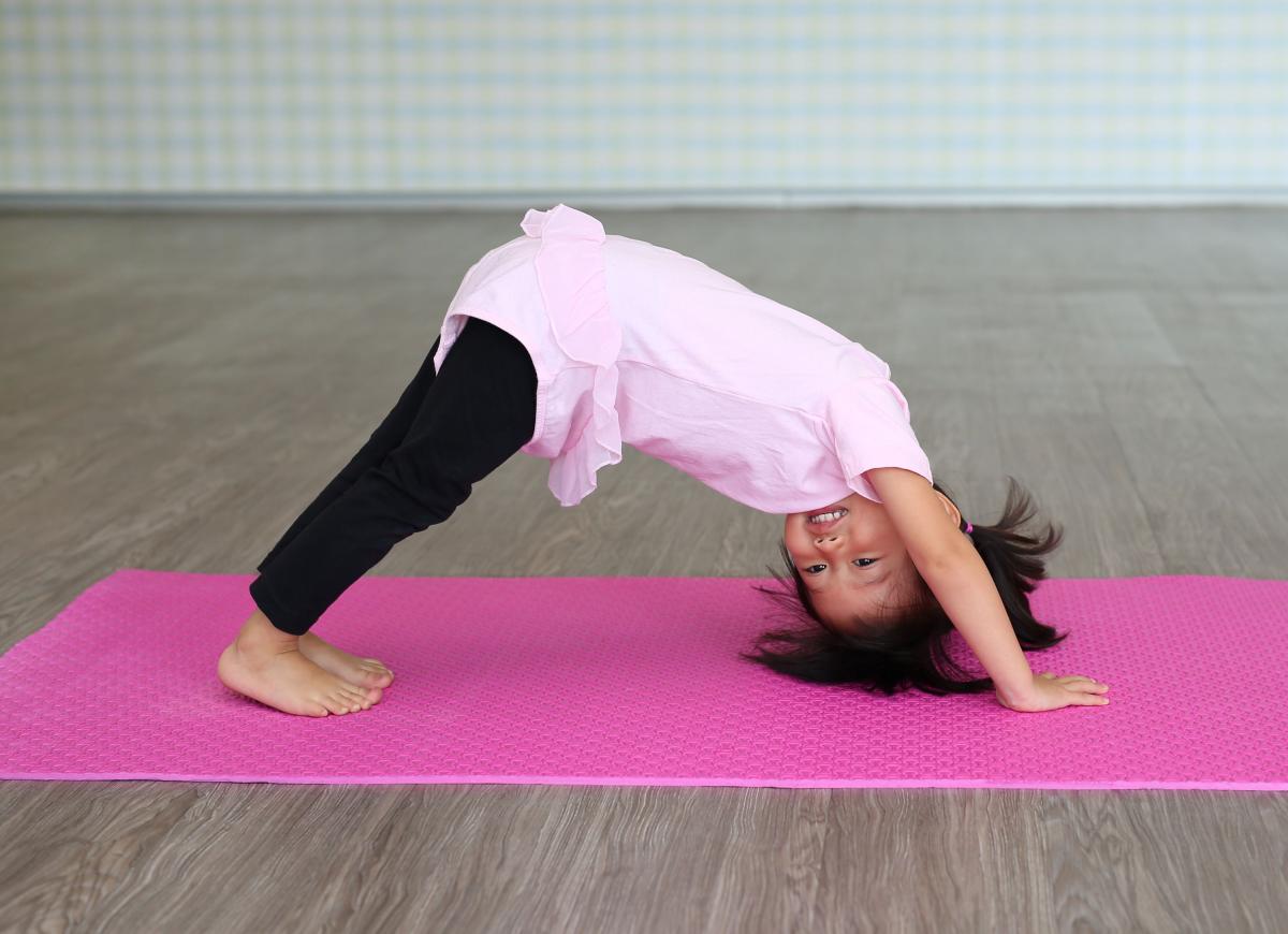 young girl in pink leotard doing yoga on a pink mat