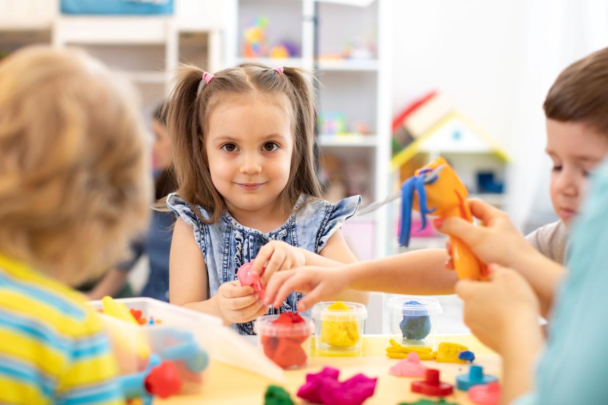children sitting at a table playing with playdough