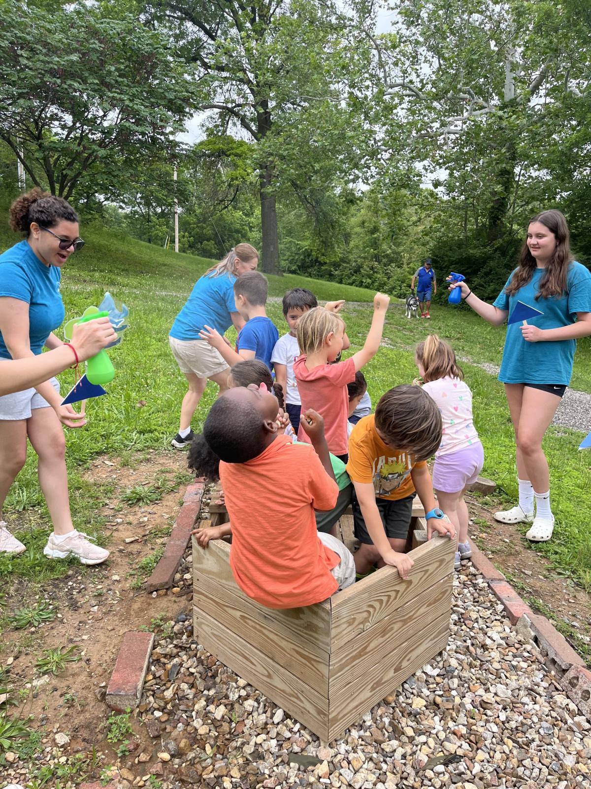 Children playing in a boat with adults spraying them outside of the boat