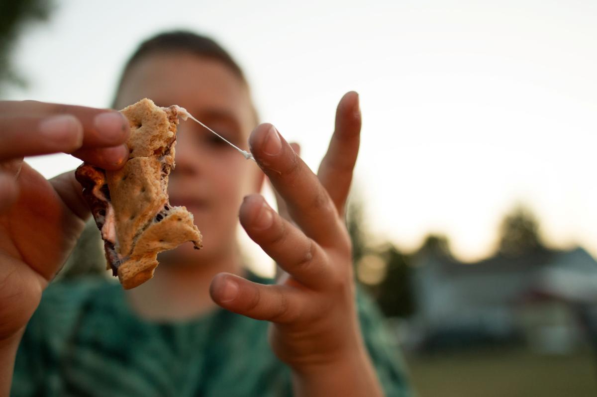 boy eating smore with marshmallow sticking to his fingers 