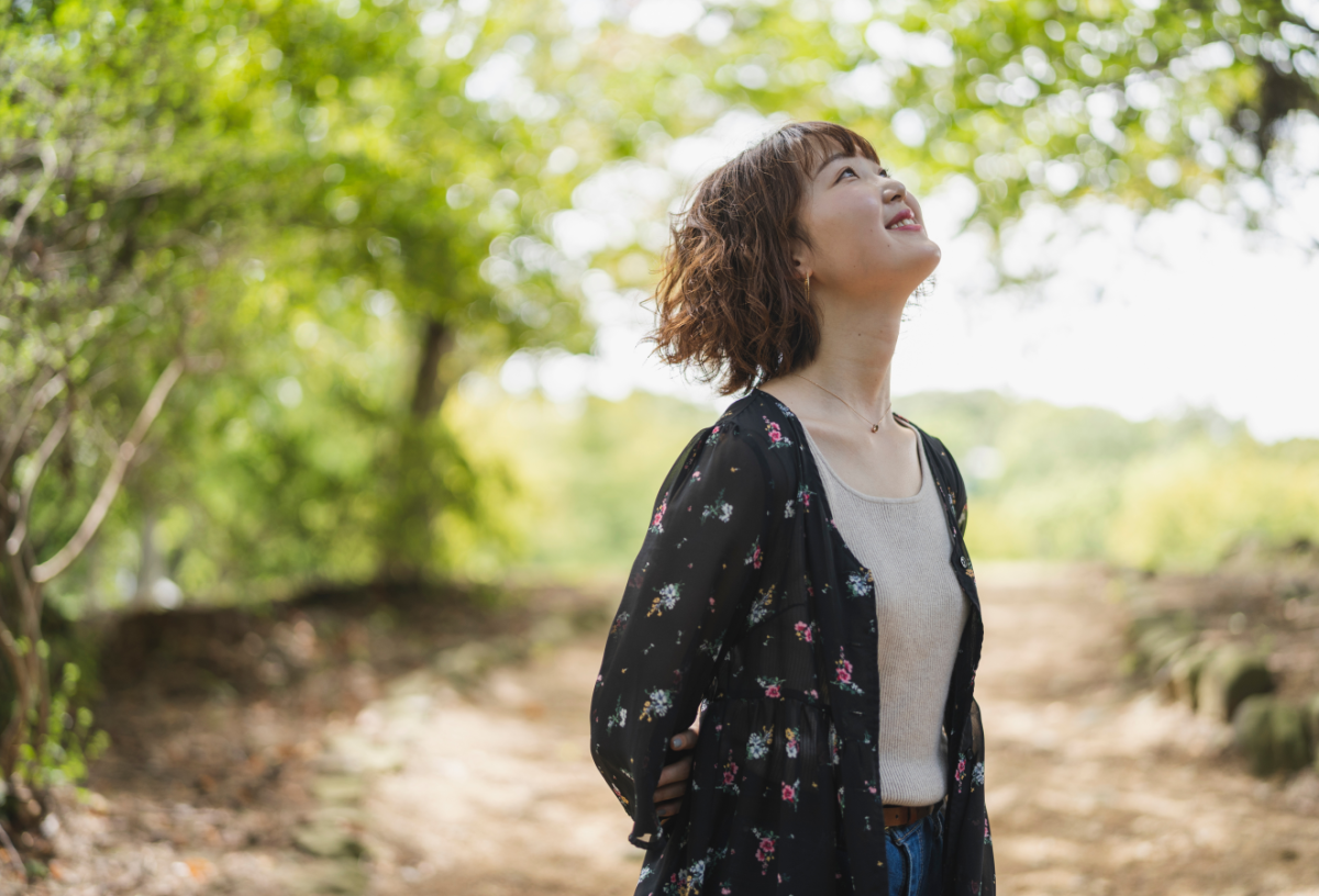 a person in the forest looking up at the trees smiling 