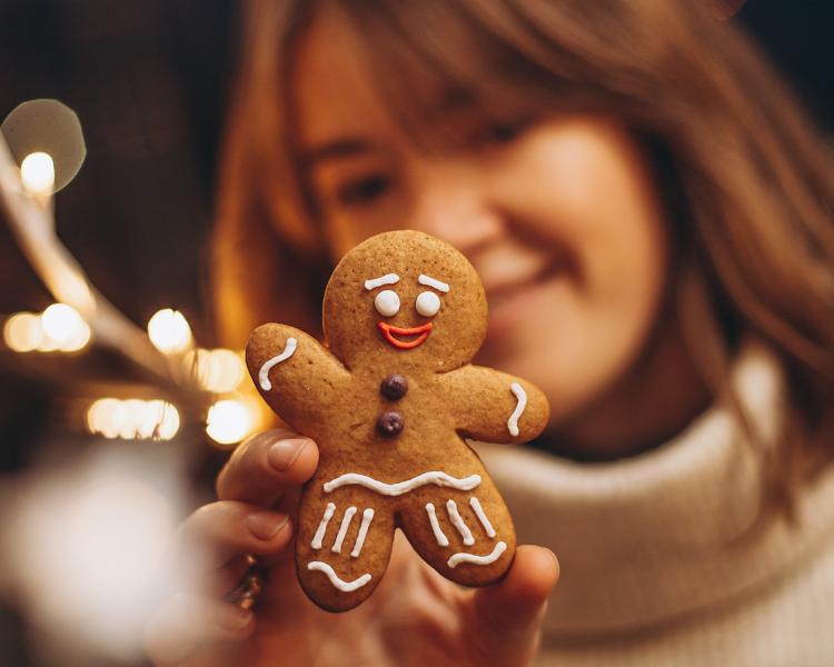 young girl holding up a decorated gingerbread man cookie
